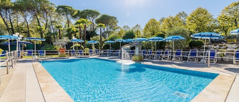Una piscina con sombrillas azules, un elemento acuático y un cielo despejado.