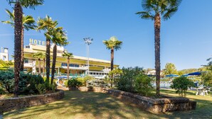 A hotel with a pool area, palm trees, and a clear blue sky. - Hotel Country Club (Capannori)