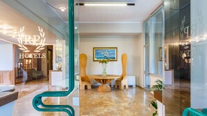A hotel lobby with a reception desk, a round wooden table with a vase of flowers, and a framed picture on the wall. - Hotel Country Club (Capannori)