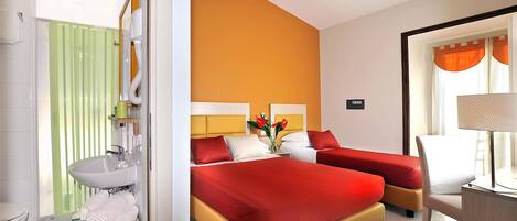 A hotel room with two beds, a sink, and a mirror.