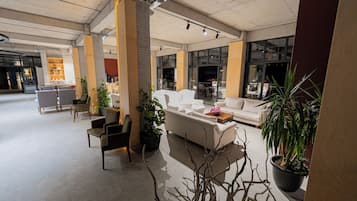 A spacious lobby with seating areas, a coffee table, and potted plants.