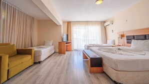A hotel room with a sofa, two single beds, a TV, a desk, and a window with curtains. - Begonville Hotel (Marmaris)