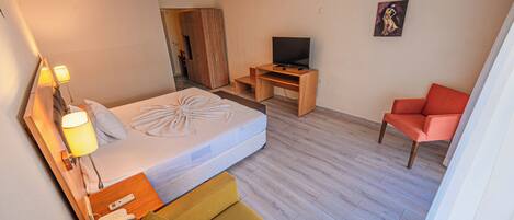 Habitación de hotel con cama, televisión, escritorio, silla y un cuadro en la pared.