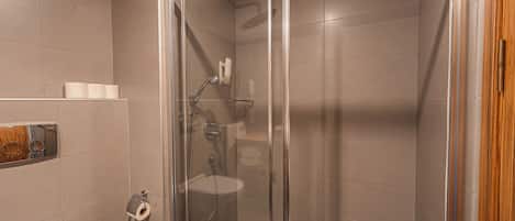 A modern bathroom with a glass shower enclosure, a toilet, and a sink.