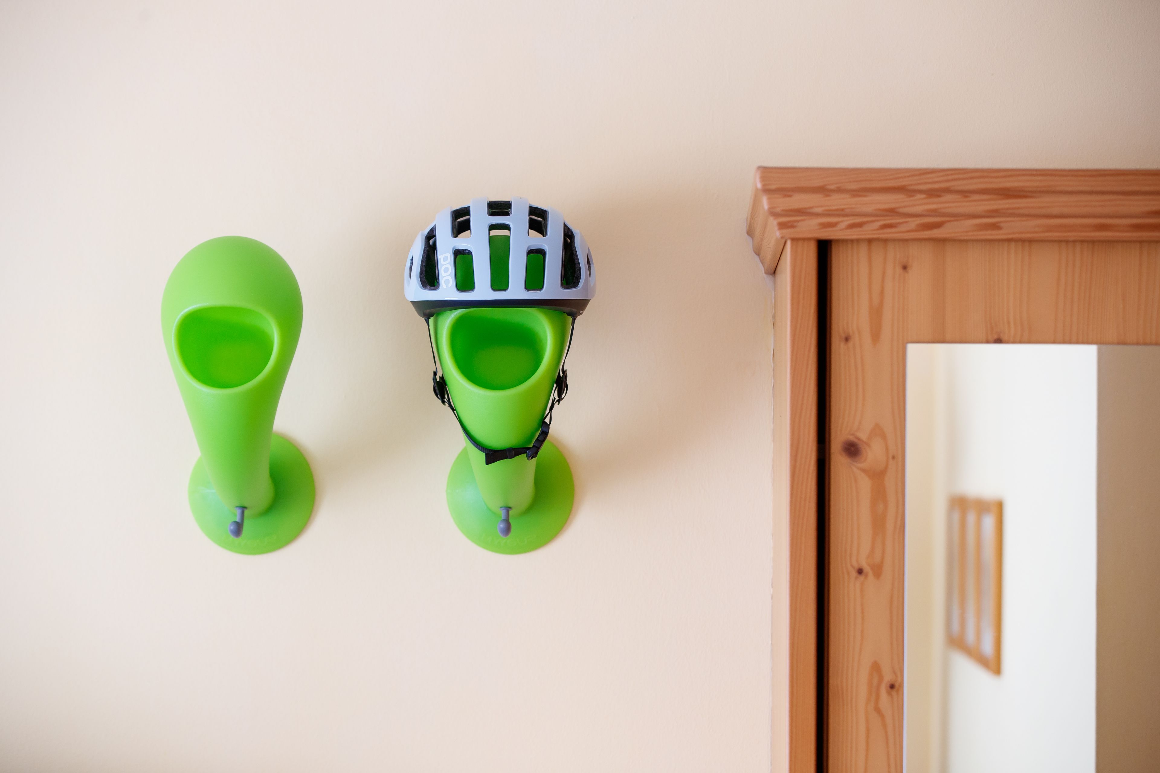 Twee groene objecten aan een muur bevestigd, waarvan er één een helmachtige constructie heeft.