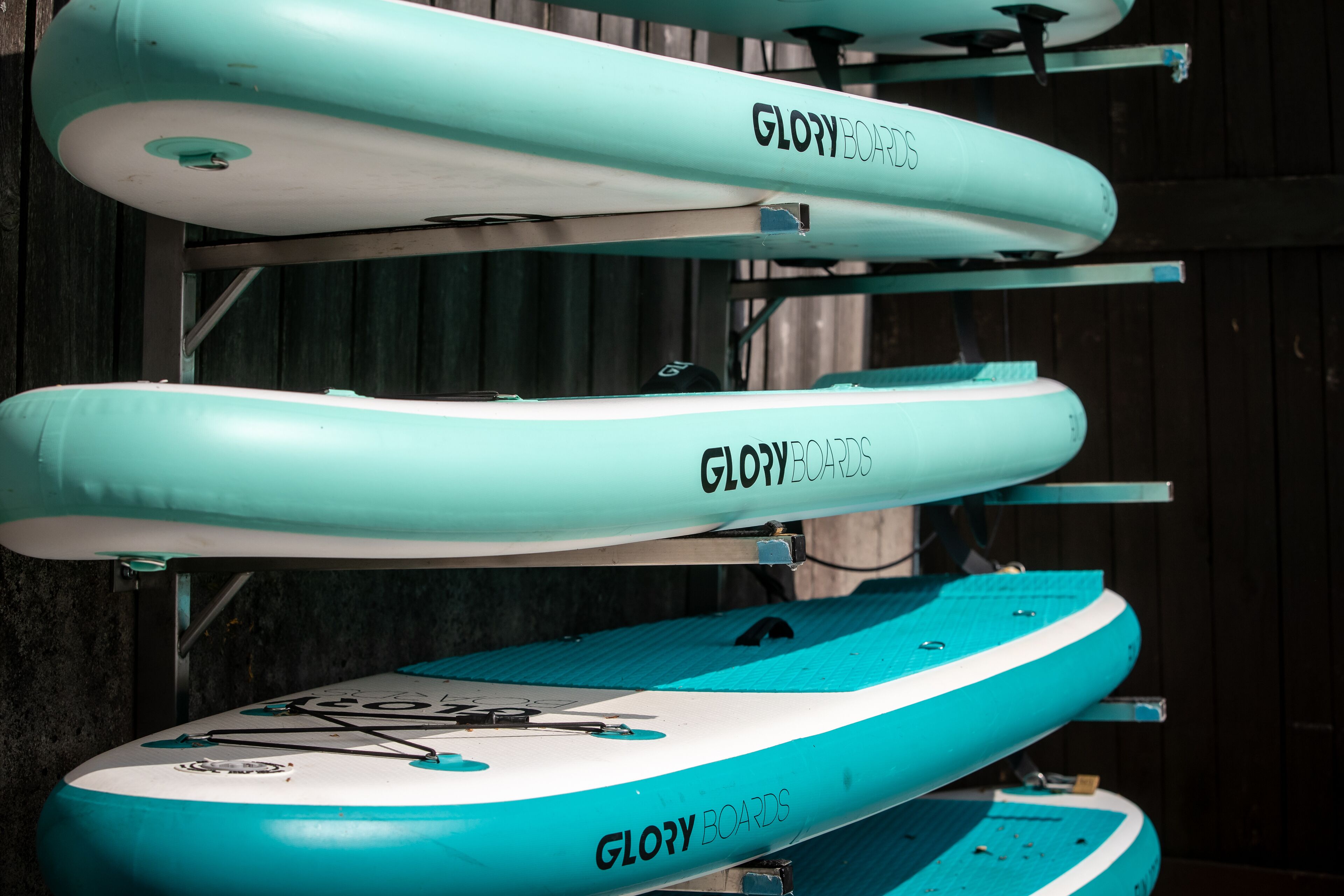 A row of surfboards with the brand "GloryBoards" mounted on a rack.
