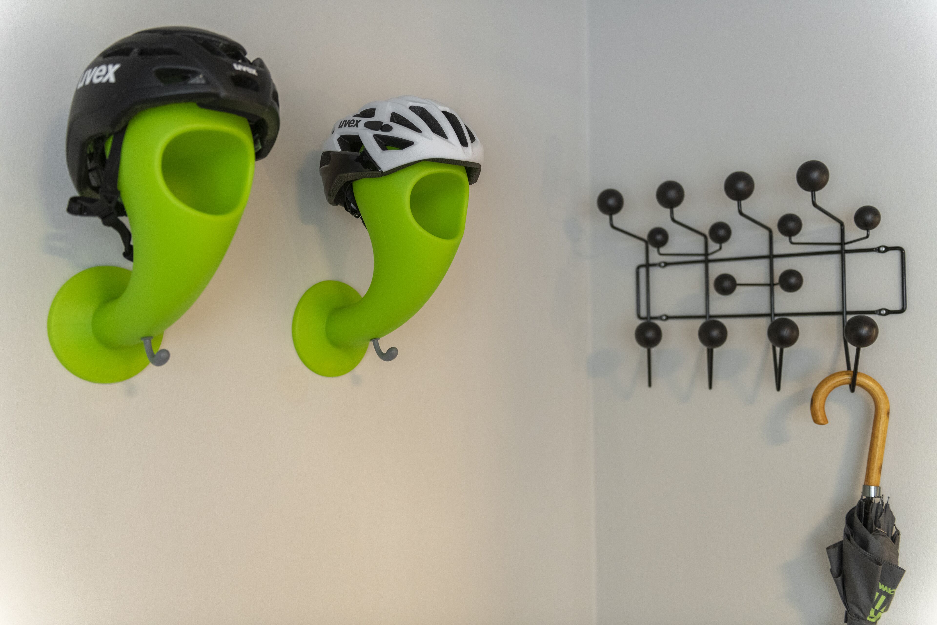 A wall-mounted rack with two helmets and a hook for an umbrella.
