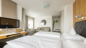 A hotel room with two beds, a TV, a desk, a mirror, and a window with curtains. - Rennrad- & Triathlonhotel Jakob (Fuschl am See)