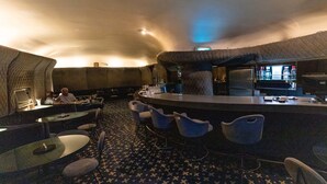 Een bar met een gebogen toonbank, barstoelen en een patroon vloer.