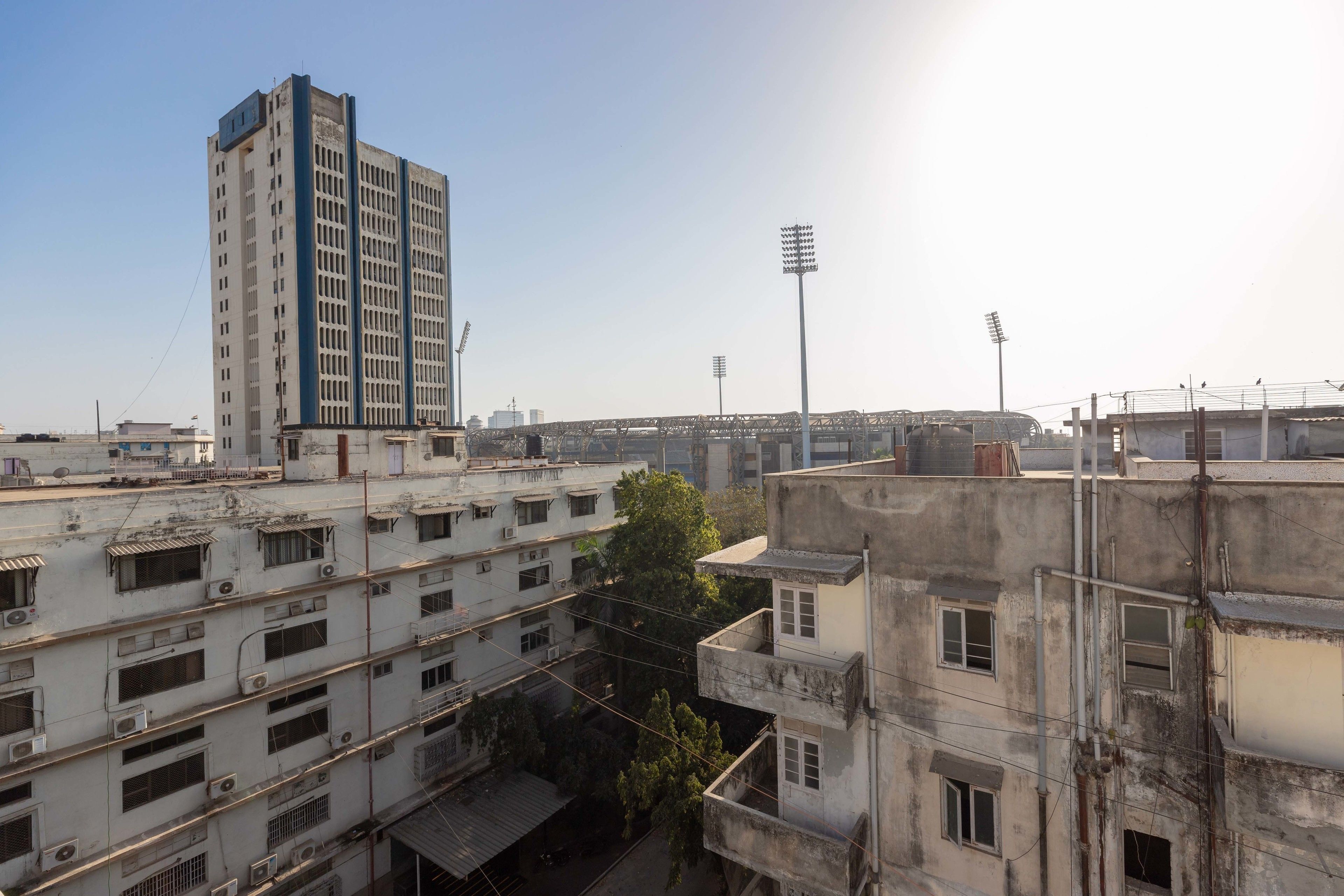 Un edificio de varios pisos con una torre central destacada, rodeado de otras construcciones residenciales.