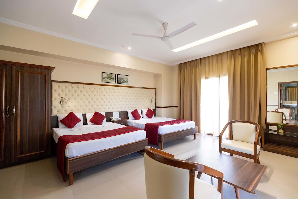 A hotel room with two beds, a ceiling fan, a desk, and a chair.