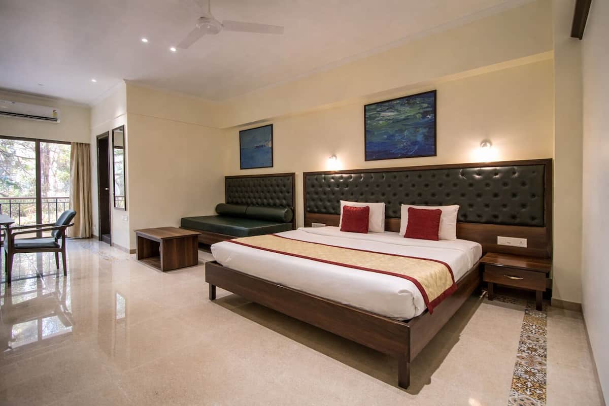 A hotel room with a large bed, a sofa, a desk, and a chair.