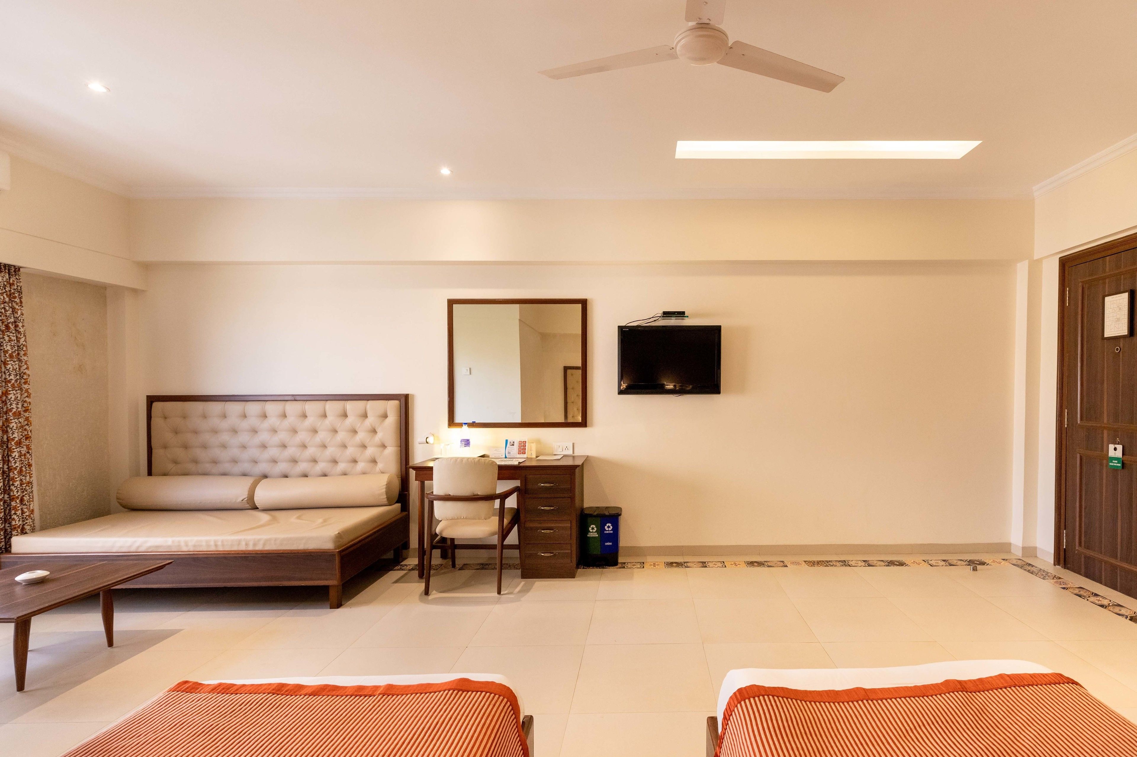 A hotel room with a bed, desk, chair, and two bedside tables.
