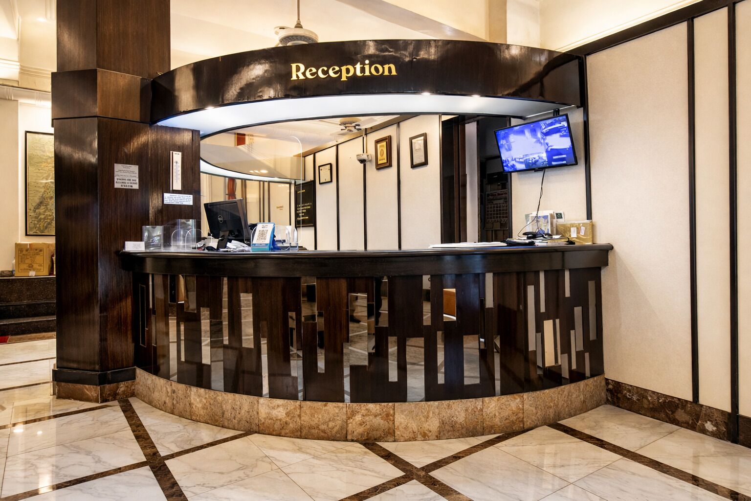 A reception desk with a 'Reception' sign, a computer, a telephone, and a television screen.