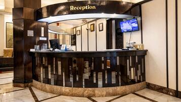 A reception desk with a 'Reception' sign, a computer, a telephone, and a television screen.