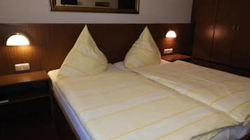 A hotel room with a bed, two bedside lamps, a mirror, and a wardrobe.