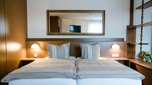 A double bed with a wooden headboard, two bedside lamps, and a large mirror above the bed. - Hotel Müller (Genthin)