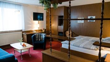 Habitación de hotel con cama, escritorio, silla, televisor y un amplio ventanal con cortinas.