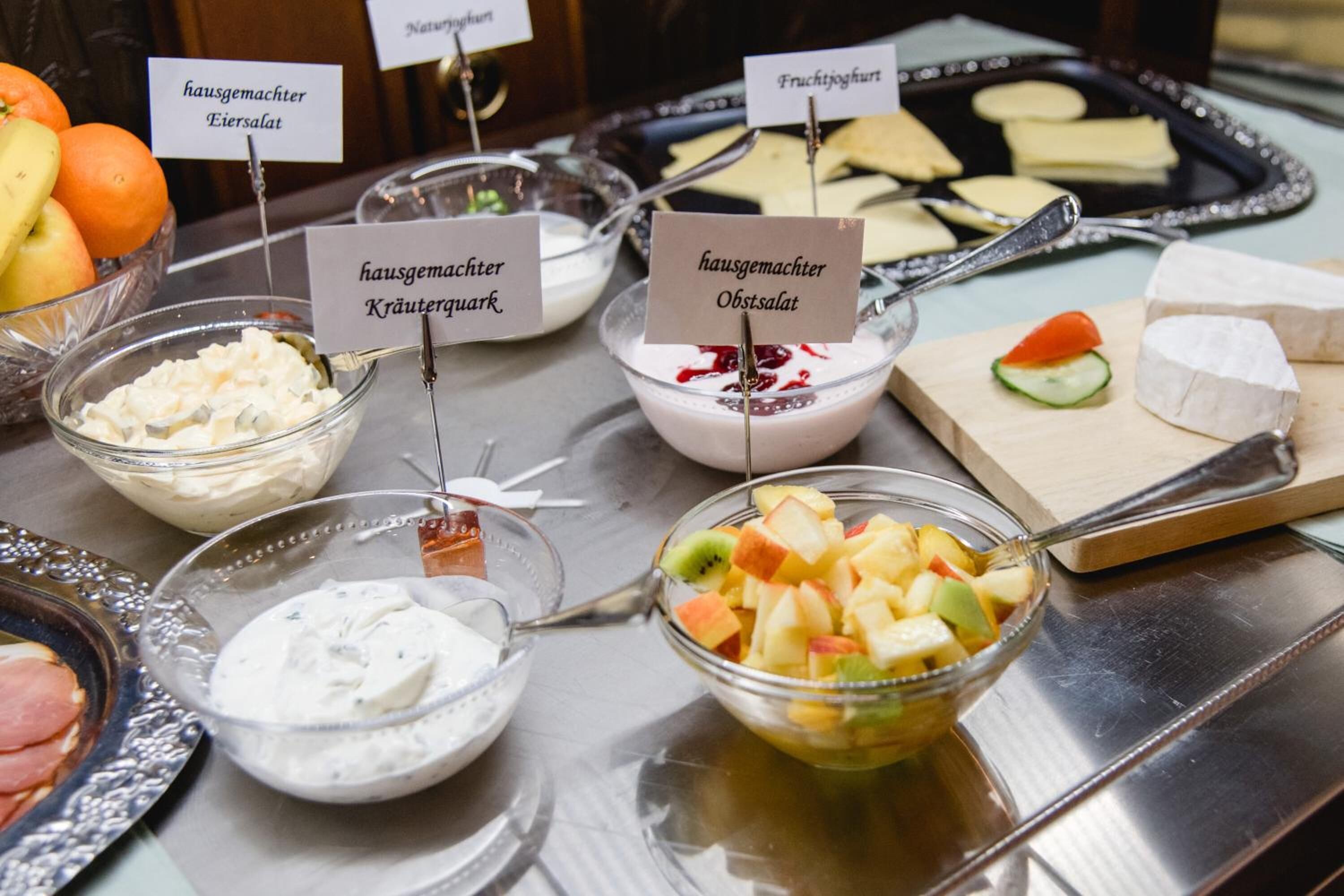 A buffet table with various food items including fruit salad, yogurt, and cheese.