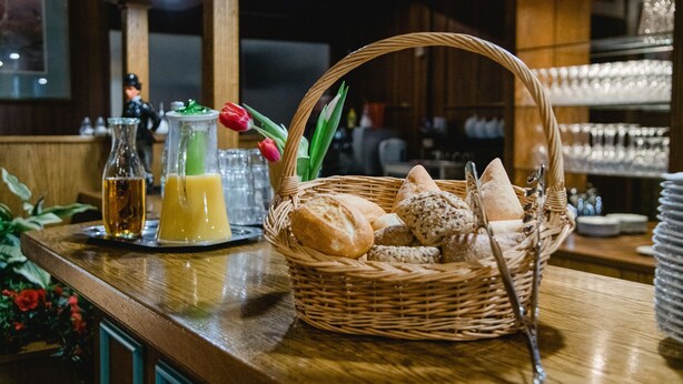A bar area with a wicker basket containing bread and a glass pitcher of orange juice. - Hotel Müller (Genthin)