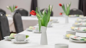A conference table set with white plates, cups, and a white vase with red tulips. - Hotel Müller (Genthin)