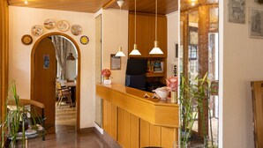 A reception area with a wooden counter, hanging pendant lights, and a mirror.