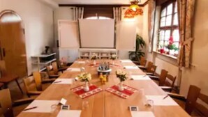A conference room with a long table, chairs, a projector screen, and a decorative hanging light.