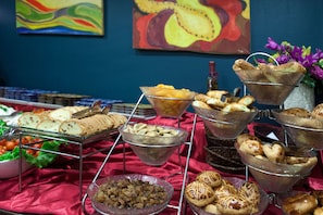 Een buffet met diverse soorten eten, zoals brood, gebak en fruit.