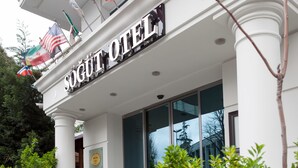 The exterior of the Sogout Hotel with a prominent sign, a balcony with flags, and a reflection of trees in the windows. -  Sogut Hotel Old City (Istanbul)