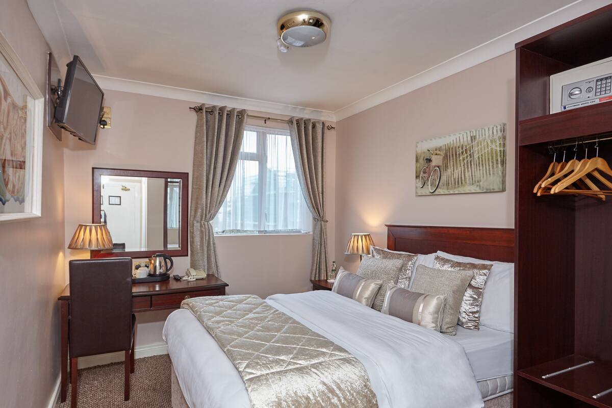 Ein Hotelzimmer mit Bett, Schreibtisch, Stuhl und Kleiderschrank.