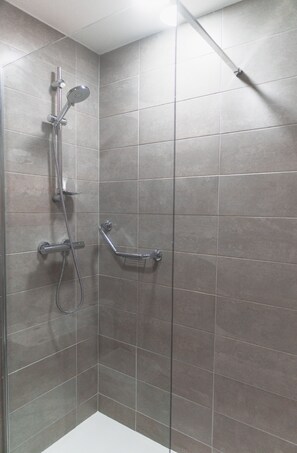 A shower area with a handheld showerhead, a wall-mounted showerhead, and a handheld showerhead with a hose. - The Uppercross House Hotel (Dublin)
