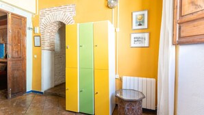 Un couloir avec un mur jaune, une arche en briques et une armoire verte et jaune.