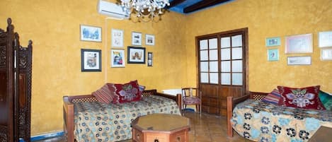 Una habitación con dos camas de madera, una mesa de madera y un ventanal grande.