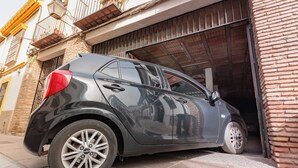 Une voiture compacte est garée devant un immeuble dont la porte de garage est visible.