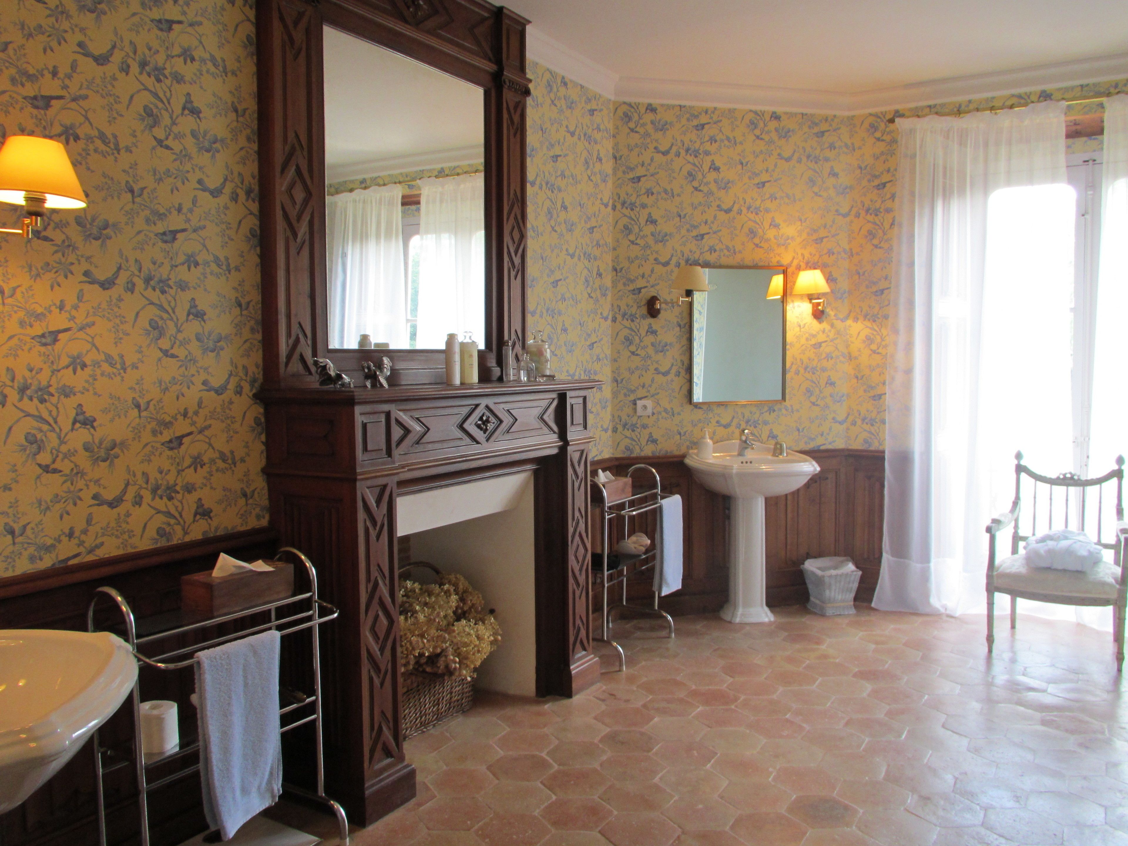 Een badkamer met een grote spiegel, een wastafel, een wastafelmeubel en een stoel.