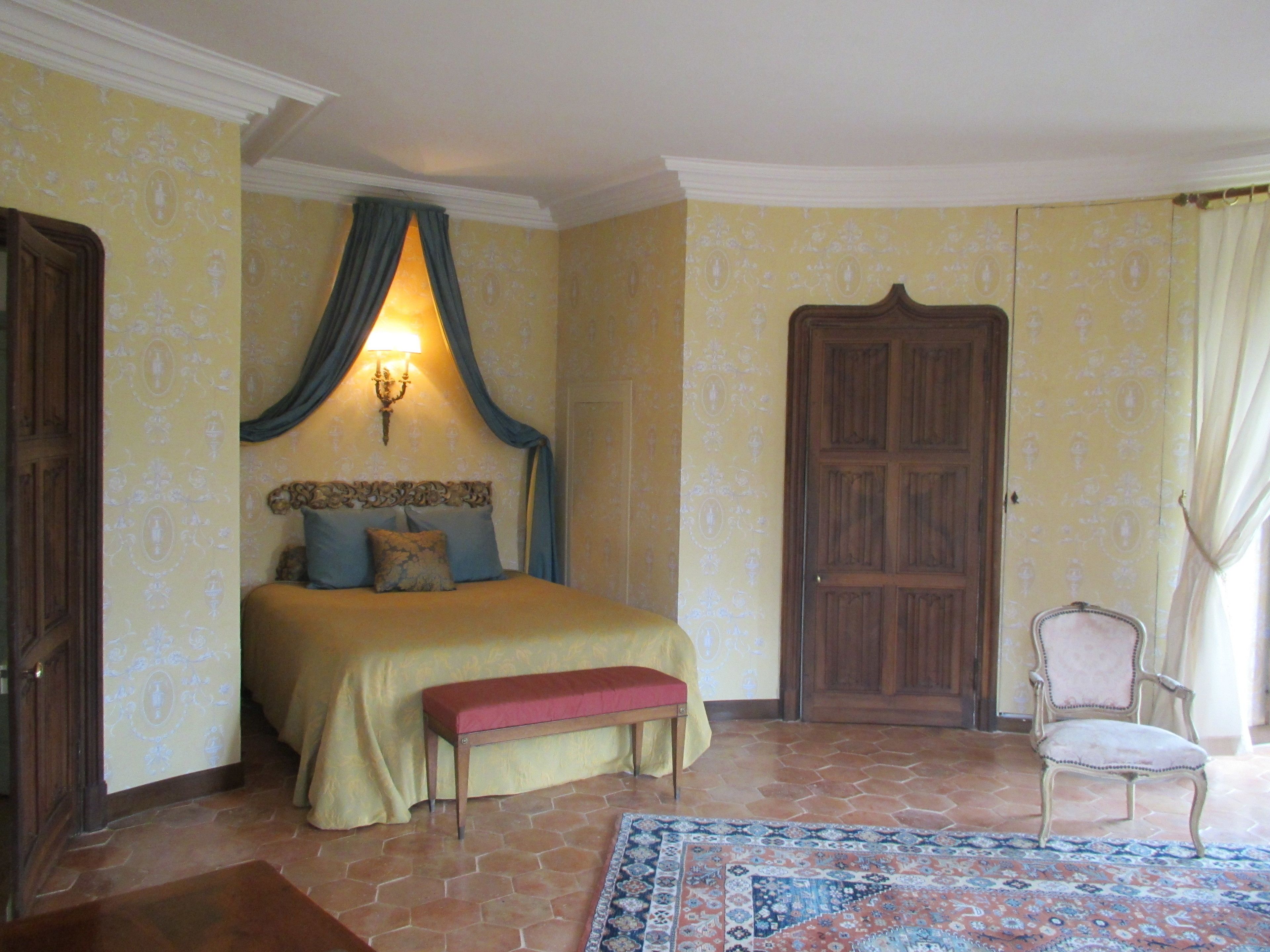 A bedroom with a bed, bench, chair, and a door.
