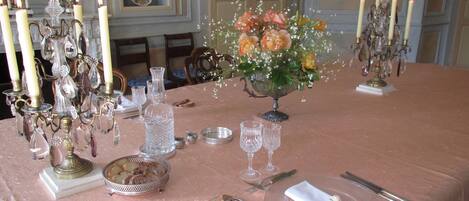 A formal dining table set with candles, glassware, and a floral centerpiece.