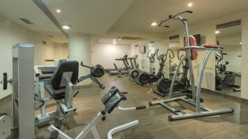 A gym with various exercise machines, including treadmills and weight stations, arranged in a spacious layout.