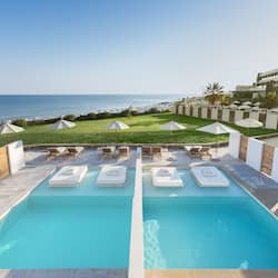 Relax by the oceanfront pool, surrounded by lounge chairs and umbrellas.