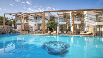 A swimming pool with clear blue water, surrounded by lounge chairs and a wooden pergola structure.