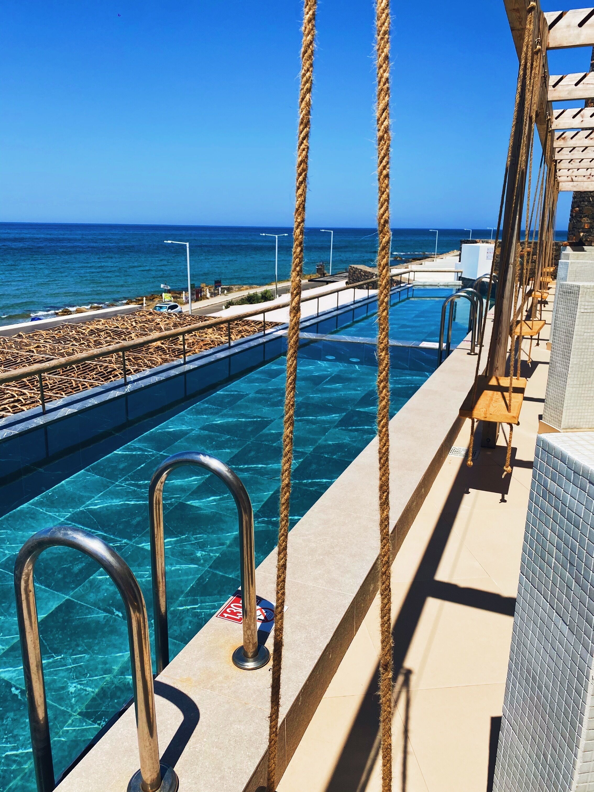 A pool area with clear blue water, metal railings, and ropes.