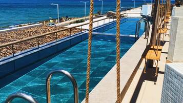 A pool area with clear blue water, metal railings, and ropes.