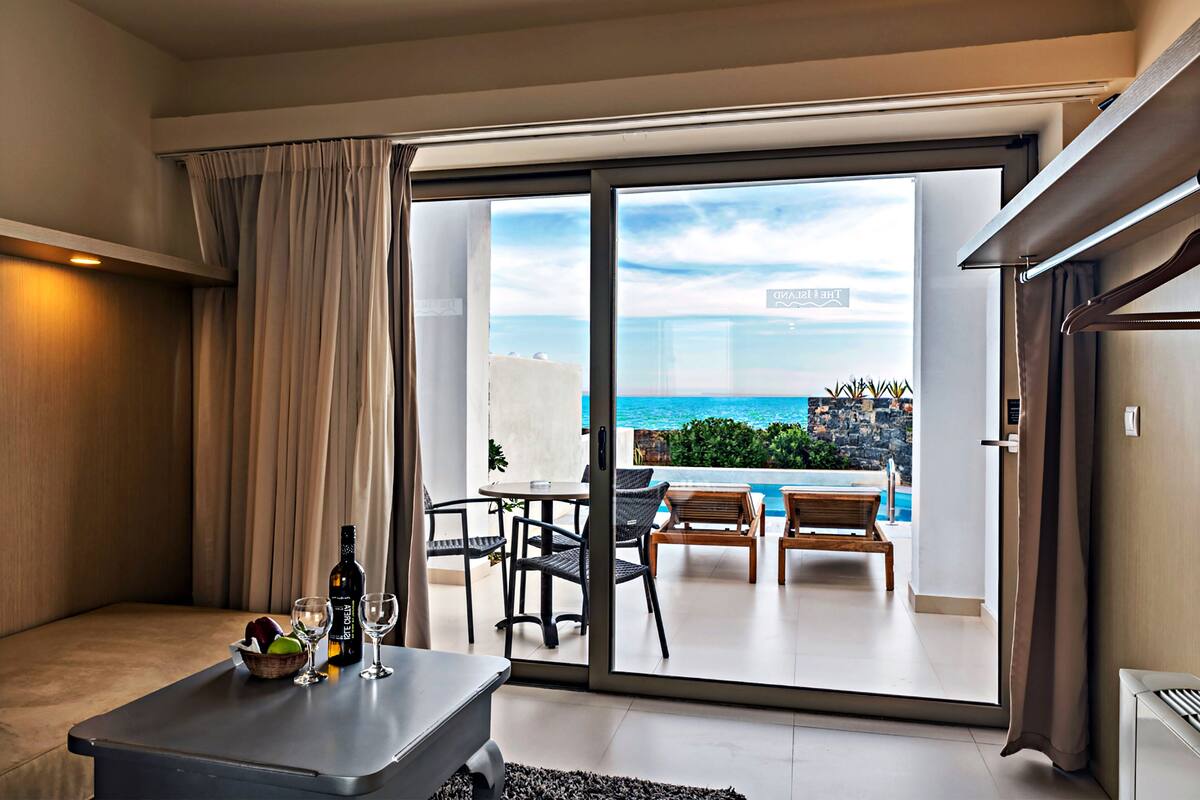 Una habitación moderna con una puerta corrediza de vidrio que da a un balcón con piscina y vista al océano.