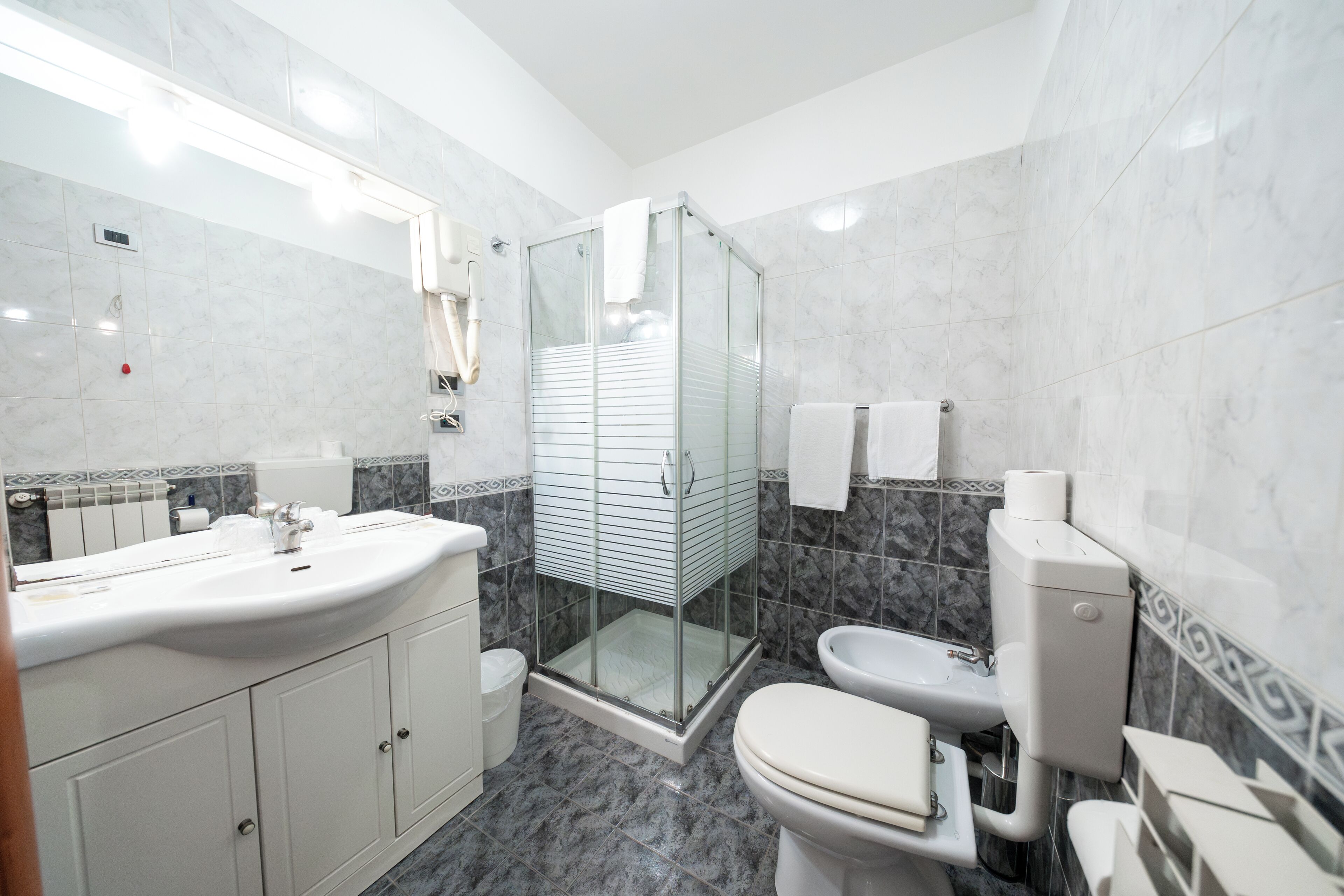 A modern bathroom with a glass-enclosed shower, a white sink, and a toilet.