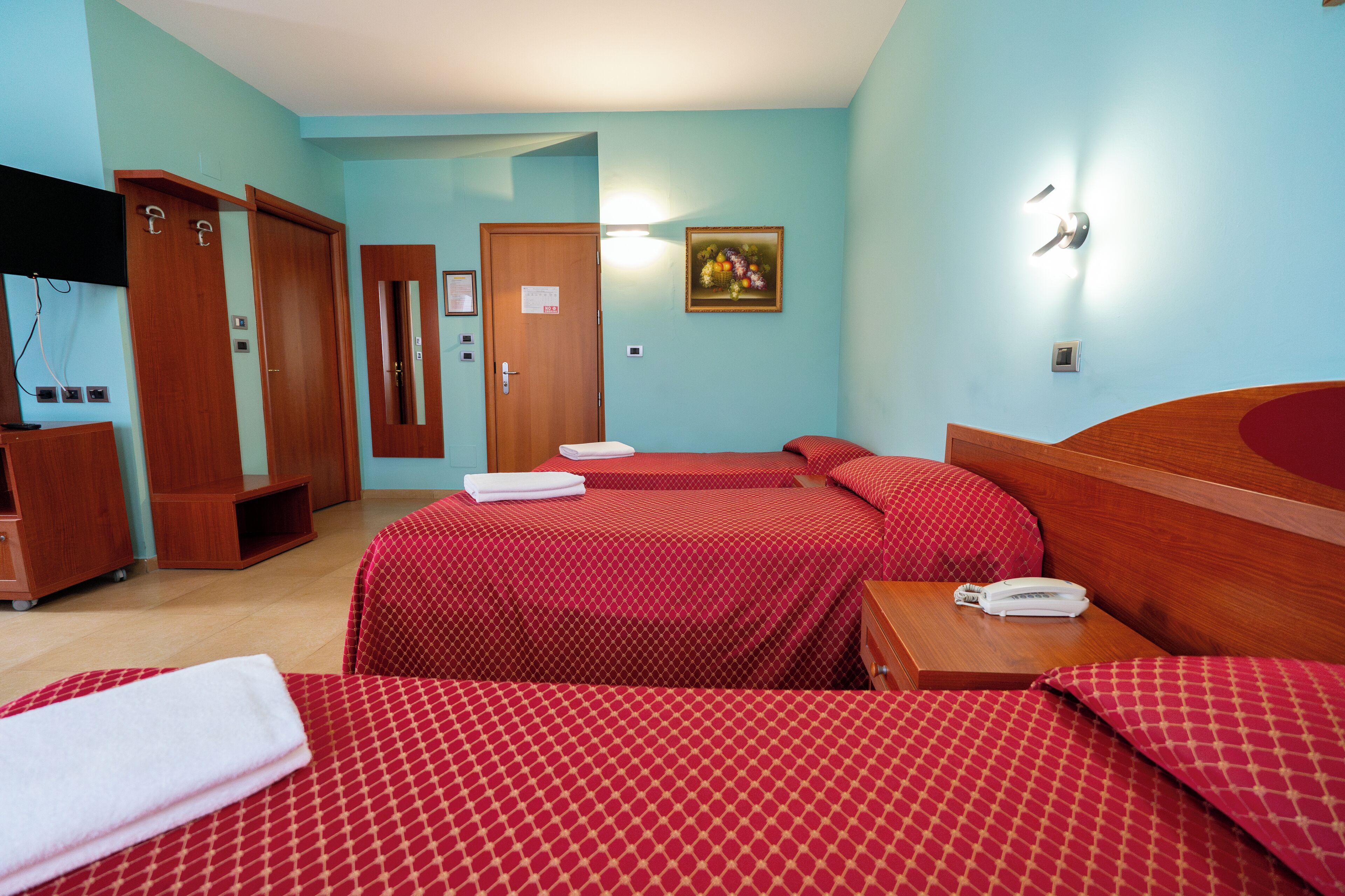 Habitación de hotel con dos camas, un armario de madera, un escritorio con teléfono y un cuadro en la pared.