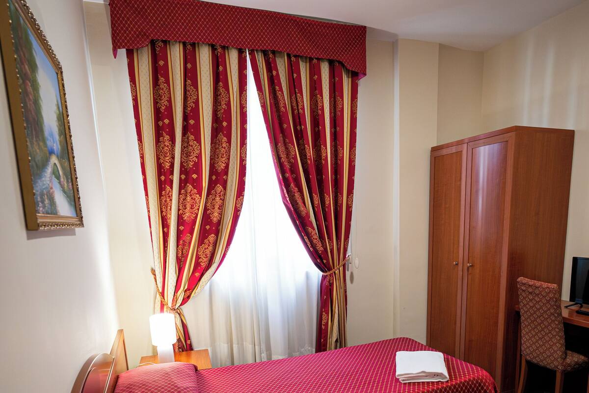 Ein Hotelzimmer mit zwei Betten, einem Schreibtisch, einem Stuhl, einem Fernseher und einem Kleiderschrank.