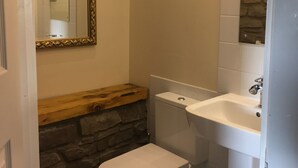 Et badeværelse med toilet, vask og spejl.