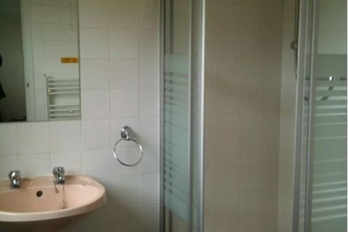 A bathroom with a sink, mirror, and glass shower enclosure.