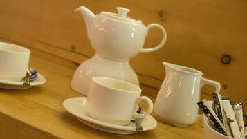 Un service à thé comprenant une théière, des tasses et un sucrier, posé sur une table en bois.