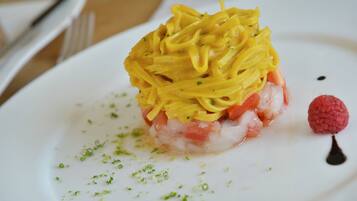A white plate with a seafood dish, garnished with green herbs and a raspberry.